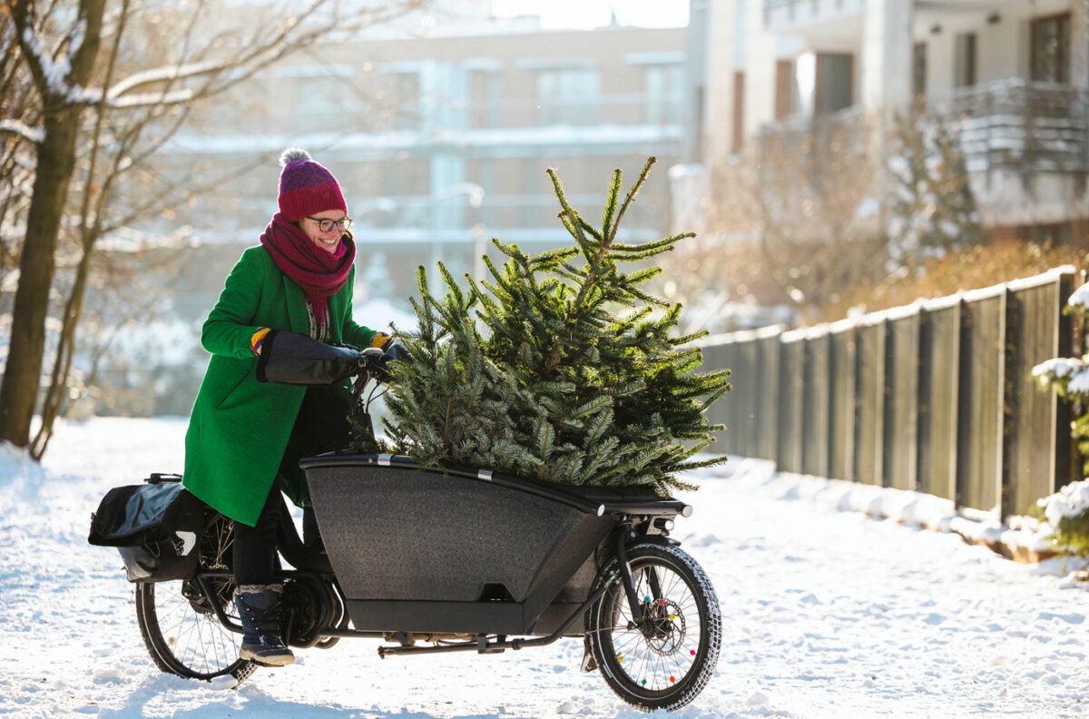 Femme transportant un sapin de Noël sur un vélo cargo